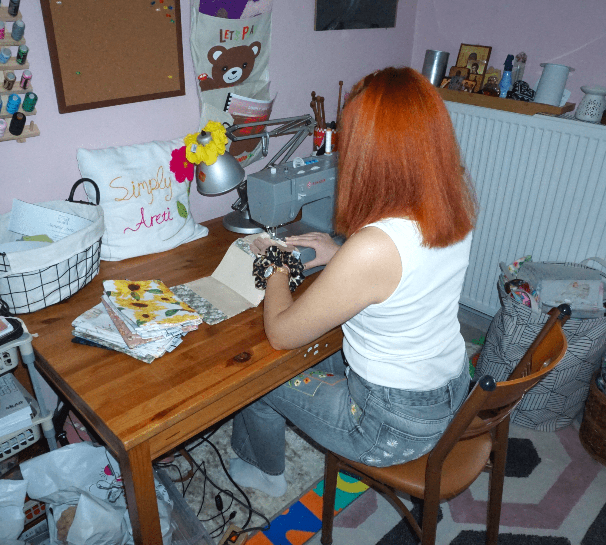 Areti sitting at a sewing machine in a home office setting